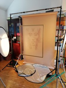 Overlay of Akhenaten suspended in front of a peachy-yellow backdrop paper, reflectors all around it.