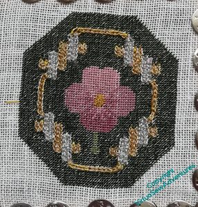 Pansy in tent stitch with gold and silver strapwork on a dark green ground.