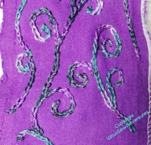 Curlicues beginning to be stitched in a variegated thread