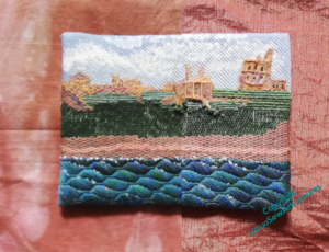An image showing the Tynemouth Priory embroidery against two orangey fabrics