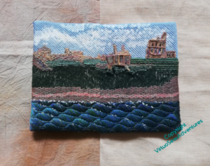 An image showing the Tynemouth Priory embroidery against two pale sandy fabrics
