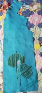 The whole pattern piece with the embroidery in place, laid over a patchwork quilt.