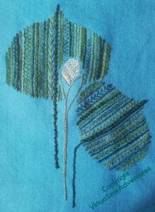 The two leaf shapes, bud between them, stitched on the turquoise tweed